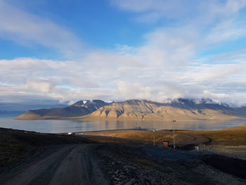 Scenic view of road by mountains against sky