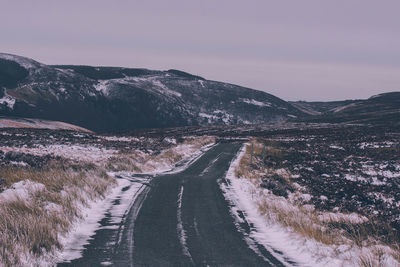 Road amidst field against sky