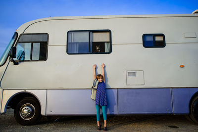 Portrait of girl with arms raised standing by motor home