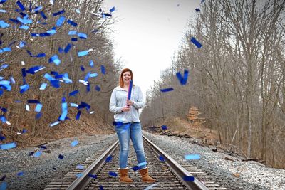 Woman blowing confetti on railroad track