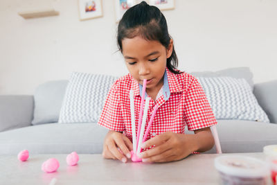 Cute asian child girl playing and creating with play dough and straws. 