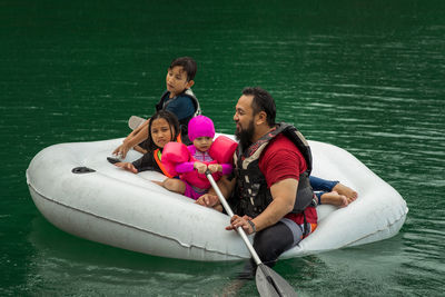 Rear view of people sitting on shore