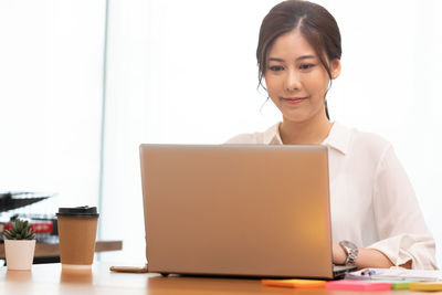 Smiling businesswoman using laptop in office