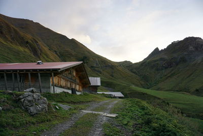 Scenic view of road amidst houses and mountains against sky