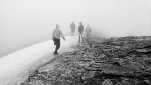 Rear view of people walking on rocks