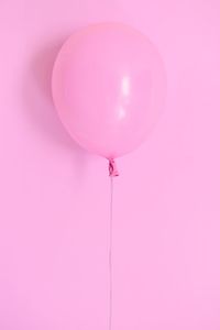 Low angle view of balloons against pink background