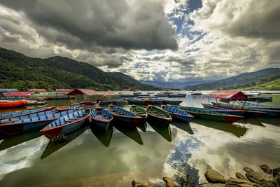 Boats moored at harbor against sky