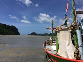 Boat moored on beach against sky
