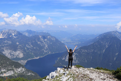 Man standing on rock by mountains against sky