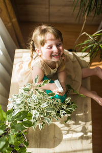 Cute girl smiling while sitting on potted plant