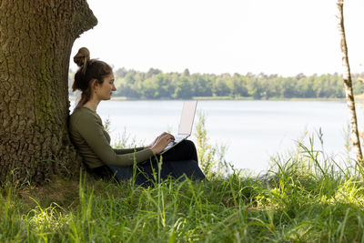 Remote freelancer work in nature on her laptop using renewable energy using solar panel.
