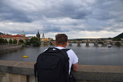 Rear view of man with backpack looking at charles bridge