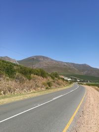 Road by mountains against clear blue sky