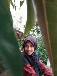 Portrait of smiling young woman against plants