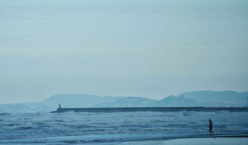 Man standing in sea against clear sky