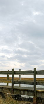 Fence on beach against sky