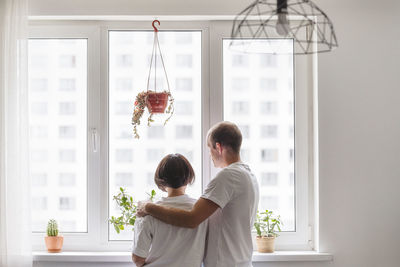 Rear view of couple walking against window