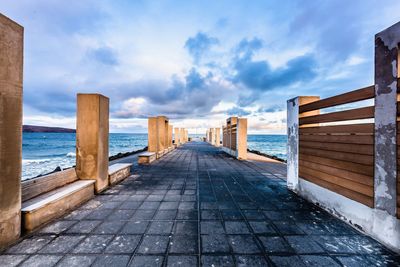 View of buildings by sea against cloudy sky