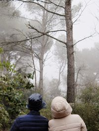 Rear view of people against trees at forest