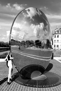 Woman standing on footbridge against cloudy sky