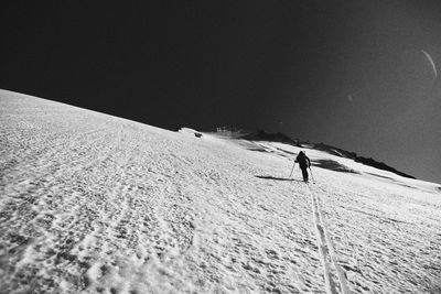 Man skiing on snowcapped landscape against sky during winter