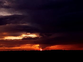 Silhouette landscape against dramatic sky during sunset