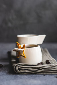 Ceramic white mugs with hot coffee drink on grey textile background