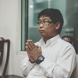 Close-up of young man sitting with hands clasped at home