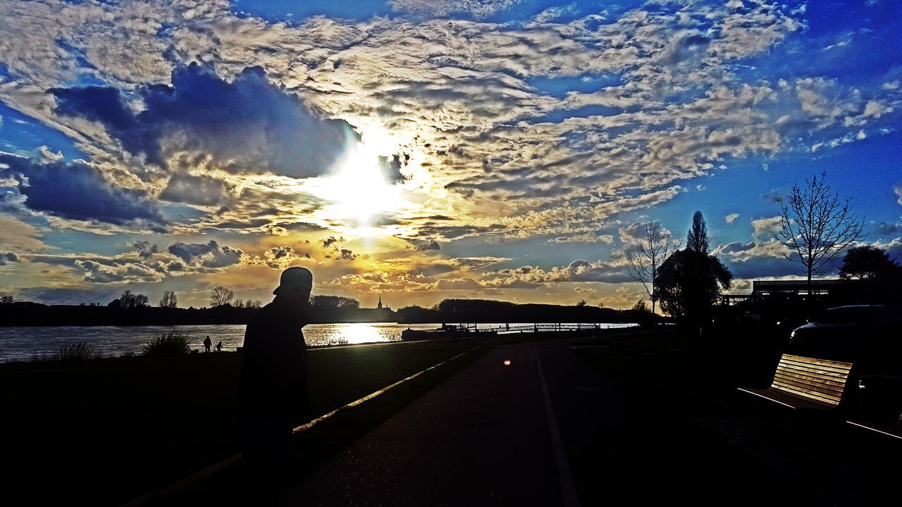 silhouette, sky, water, mountain, sunlight, scenics, nature, beauty in nature, tranquility, river, tranquil scene, cloud - sky, built structure, sunset, railing, mountain range, blue, lake, cloud, outdoors