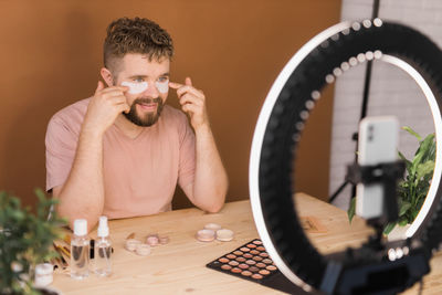 Portrait of young man using mobile phone while sitting at home