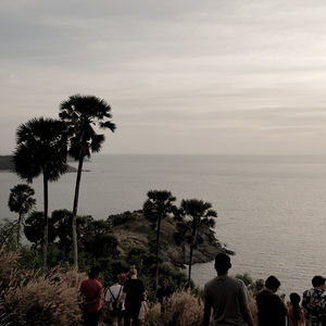 Silhouette people on beach against sky during sunset