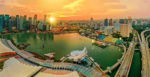 Panoramic view of river and buildings against sky during sunset