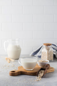 Oatmeal vegetable milk in a mug on the table with oatmeal in a bowl.