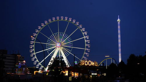 Low angle view of illuminated ferris wheel against sky at night