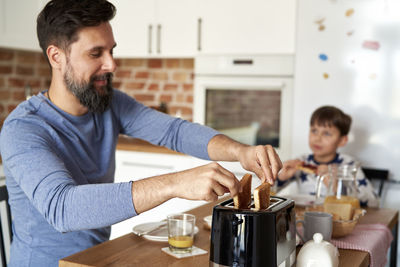 Side view of man using mobile phone at table