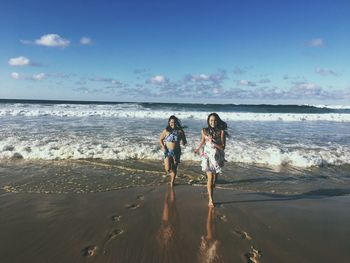 Friends standing on beach against sky