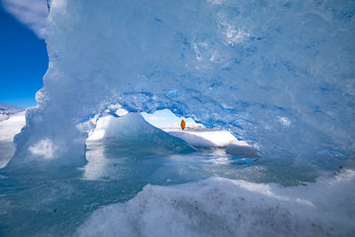 Back view of unrecognizable traveler hiker admiring spectacular scenery of frozen seashore with ice and snow in winter in iceland