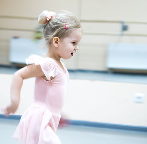 Side view of cute girl ballet dancing in studio