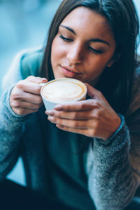 Young woman holding coffee cup at sidewalk cafe in city