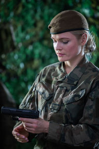 A lady soldier watches and inspects a gun. a soldier in full uniform.