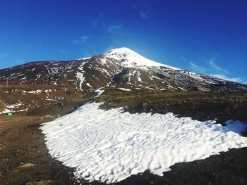 Snow covered mountain against blue sky