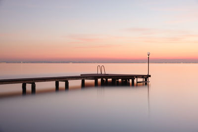 Pier over sea against sky during sunset