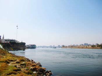 Scenic view of river by buildings against clear sky