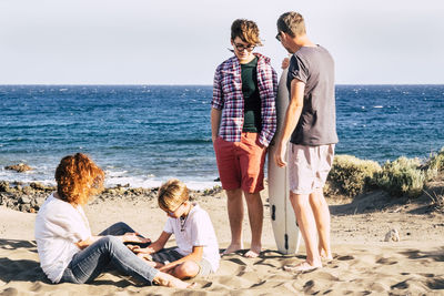 Family enjoying at beach against sky