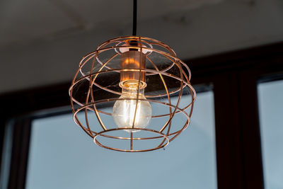 Low angle view of illuminated light bulb hanging from ceiling