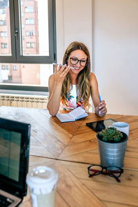 Young woman using mobile phone while sitting on table