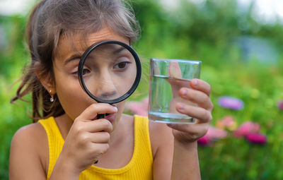 Girl looking at water through magnifying glass