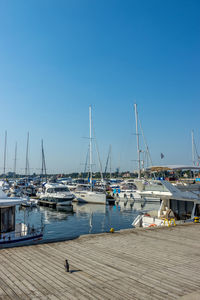 Boats moored at harbor against clear blue sky