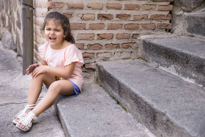 Smiling boy sitting on stone wall