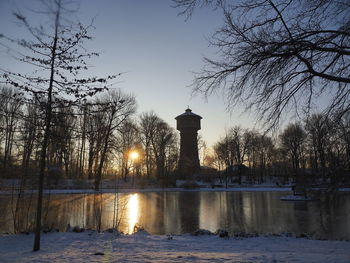 Scenic view of lake by building against sky during winter